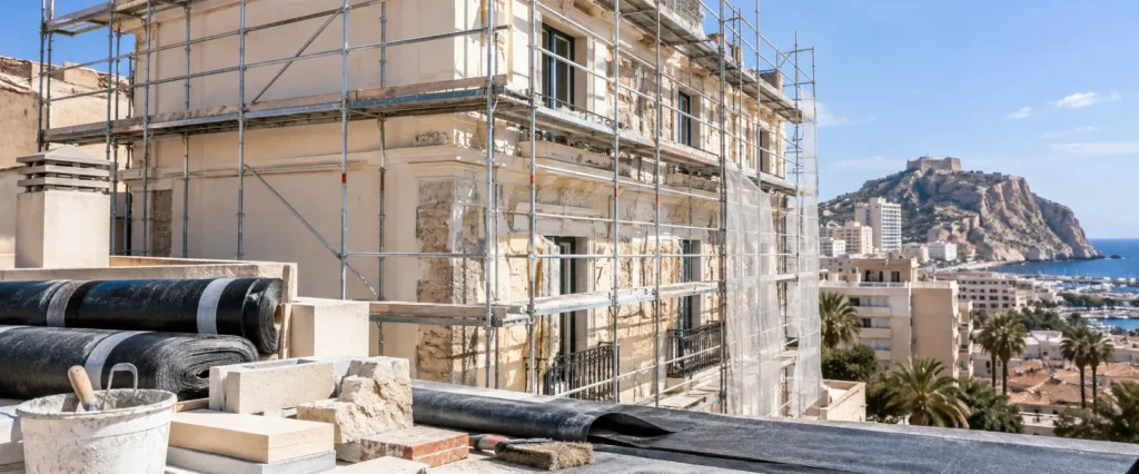 Fachada en rehabilitación con andamio, impermeabilización y materiales de obra